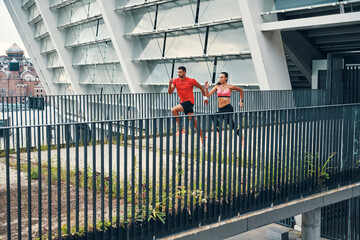 Full length of young beautiful couple in sports clothing enjoying morning jogging while practicing outdoors