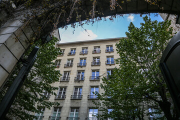 European building with many windows seen from an arch with green trees