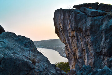 view of the bay of the sea through between stone rocks, cliffs, evening sunset