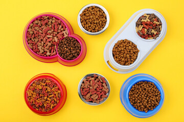 Obraz na płótnie Canvas Dry pet food in bowls on yellow background