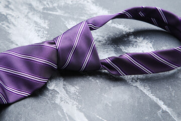 Striped necktie on grey background