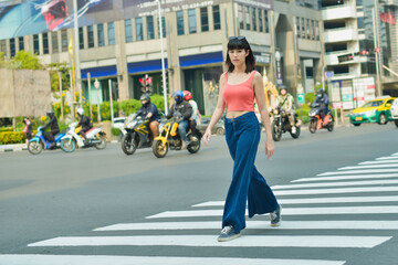 Beautiful asian woman crossing on crosswalk and looking camera.