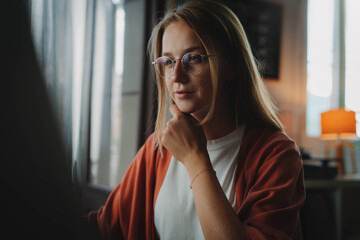 Beautiful happy woman in eyewear sitting at home interior working on computer looking at monitor display browsing internet, Pretty millennial girl using compute preparing for online learning program