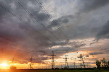 High-voltage power lines passing through a green field of wheat, on the background of a cloudy sky