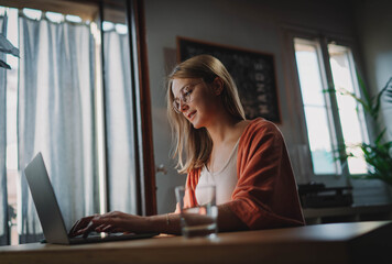 Attractive smiling woman working at home using computer, Young good-looking female person wearing...