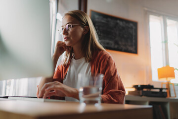 Young woman customer assistant working on computer selling products and taking orders from clients, Beautiful businesswoman thinking about something while sitting front computer reading email