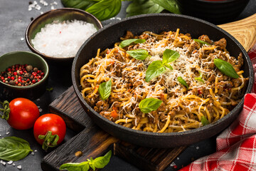 Pasta Bolognese in the skillet at black table.