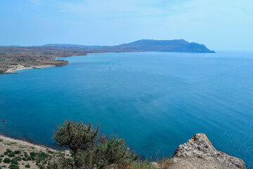 view of beautiful coast with green trees of bay of sea with blue water among hills and high mountains. Crimea, Russia, summer sunny landscape
