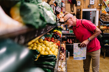 Concentrated pensioner buying fruits in grocery