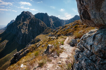 Hiking trail through golden grasses and wild mountain scenery on a sunny day, near Stellenbosch, South Africa.