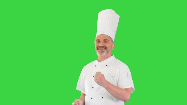 Mature chef with beard and in white uniform dancing on a Green Screen, Chroma Key.