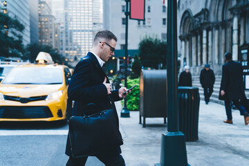 Male with smartphone crossing city road