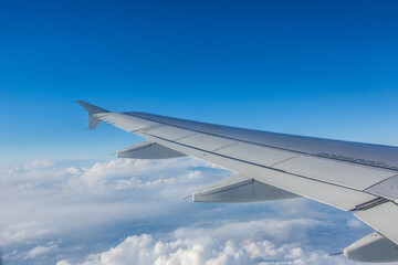 Plane wing visible cruising high above the clouds