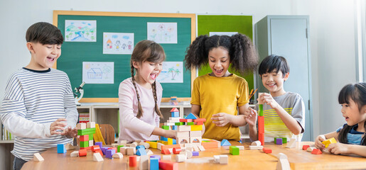 Portrait of asian caucasian little children playing colorful blocks. Learning by playing education group study concept. International pupils doing activities brain training in primary school.