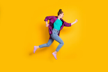 Full body profile photo of attractive teen lady jump high up run race marathon excited to win rushing competition wear casual plaid shirt sneakers jeans isolated yellow color background