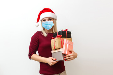 Easy to buy with online shopping! Satisfied young woman with medical mask standing and holding present, looking at camera. Isolated, studio shot, grey background