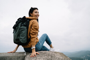 Smiling asian female traveler sitting on destination during sightseeing tour enjoying vacation...