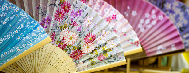 Japanese paper fans. Several folding fans  with floral patterns displayed in a souvenir shop in...
