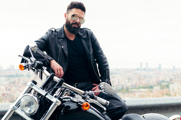 man dressed in leather poses with his motorcycle © Raul Mellado