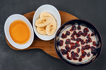 Vegetarian oatmeal porridge with dried red berries, banana and honey