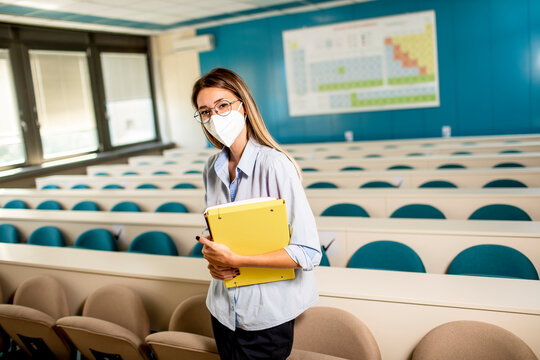 Female student wearing face protective medical mask for virus protection standing at lecture hall