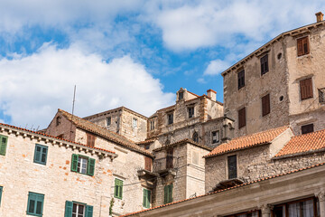 Fototapeta na wymiar Old medieval buildings against a blue sky with clouds in Sibenik, Croatia