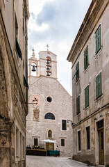 Fototapeta na wymiar Medieval church with bell tower, clocks and cross in Sibenik; Croatia