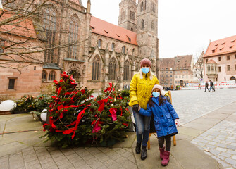 Obraz premium mother and daughter in medical masks have fun on the street near the Christmas tree. Family happiness, holiday, joy, vacation, games with a woman. New Year's