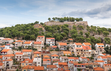 Fototapeta na wymiar View of the fortress on the hill and houses with red roofs of Sibenik, Croatia