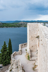 Fototapeta na wymiar Medieval tower and walls of the fortress on the background of the Adriatic sea and islands on the horizon in Sibenik, Croatia