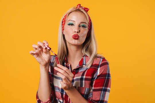 Image of pleased charming pinup girl using lip gloss