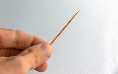 Toothpick in boy hand on plain white isolated background