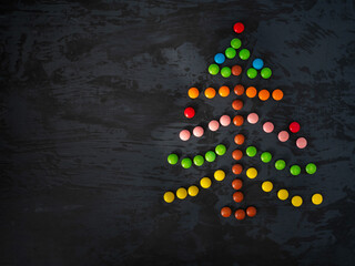 Christmas tree made of colored round caramel on a dark table