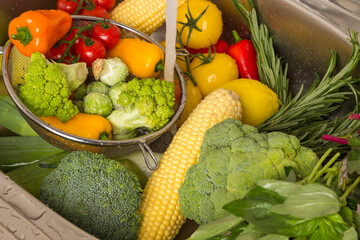 Colored vegetables in metal colander. Washing vegetables in the sink