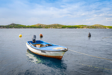Fototapeta na wymiar Wooden boat on a leash near the sea shore in Sibenik, Croatia