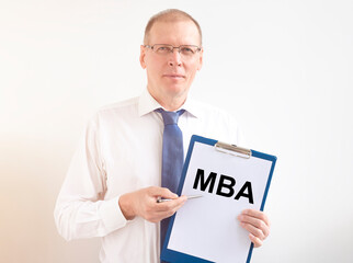 Business education concept. text MBA acronym on white paper board in businessman hands over white...
