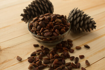 Pine nuts not peeled in a bowl on a wooden background.