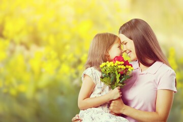 Fototapeta premium Mother and daughter with bouquet of flowers on blurred background.