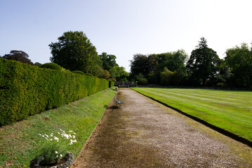 Gravel path with empty benches over looking a lawn