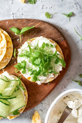 Tasty breakfast. Sandwich with crispbread, ricotta, cucumber and microgreens top view. Soft focus. Healthy vegetarian food. Sandwich with cream cheese and herbs on a concrete background.