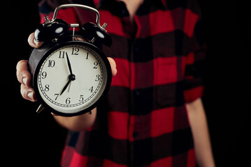 Woman in red shirt holding vintage alarm clock and showing you the minutes and secods. Black alarm...