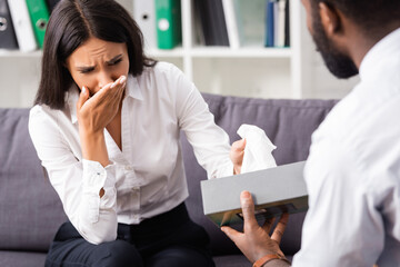 selective focus of african american psychologist giving paper napkin to crying woman