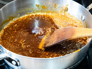 cooking salted butter caramel sauce at home kitchen - stirring melted mixture of sugar and butter...
