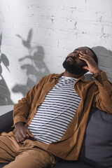 African american man sitting on couch with closed eyes