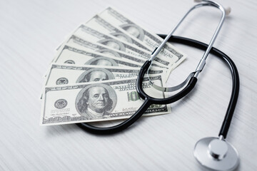 Selective focus of stethoscope and dollar banknotes on white table