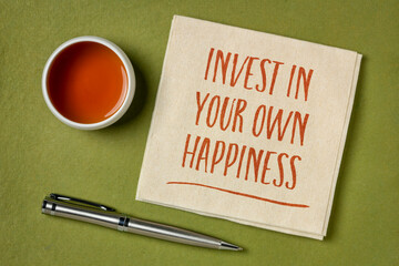 invest in your own happiness - handwriting on a napkin with a cup of tea, lifestyle and personal development concept