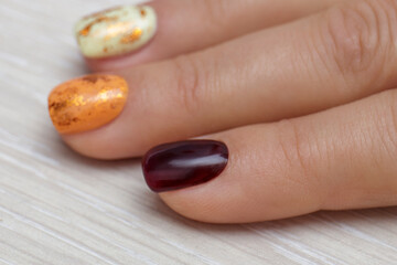 Fashionable fantasy manicure in warm colors: burgundy, orange and yellow. Woman's hand.