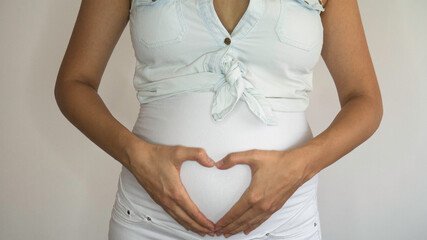 Close up of pregnant woman whit hands heart shape on her belly. 