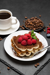 portion of Classic tiramisu dessert with raspberries and blueberries and cup of coffee dark concrete background