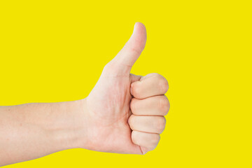 Thumb up isolated on yellow. Approval sign background. Hand showing OK symbol.